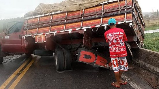 Imagem Após quebra de eixo, caminhão para com carroceria sobre mureta de ponte