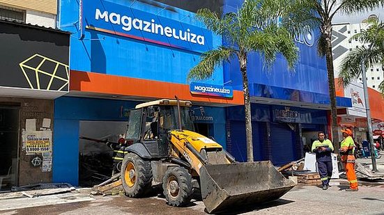 Foi preciso utilizar uma retroescavadeira para retirar os entulhos da frente da loja, para que os bombeiros pudessem entrar no local. | Gabriel Amorim / TNH1