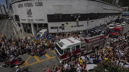 Fãs de Pelé acompanham a saída do corpo do Rei do futebol do estádio Vila Belmiro, na Baixada Santista, que segue para um cortejo e depois será enterrado no cemitério vertical Memorial Necrópole Ecumênica, na tarde desta terça-feira | Bruno Santos / Folha…